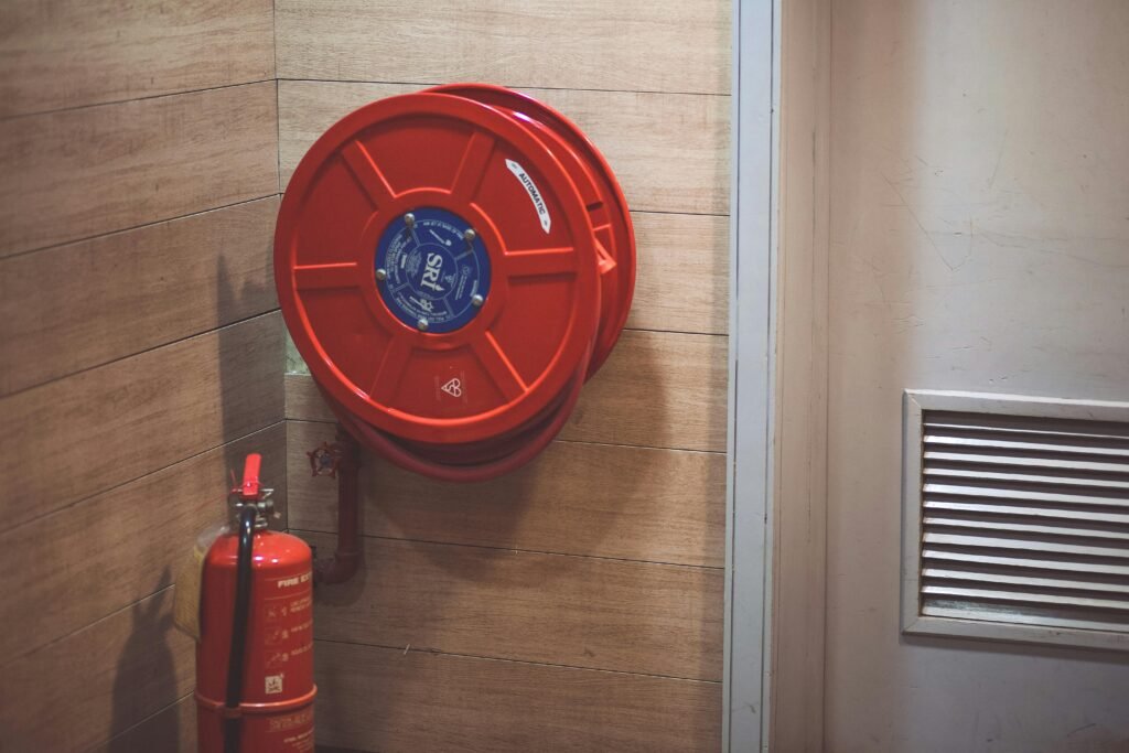 Fire hose and a Fire extinguisher in a building Red fire hose and extinguisher inside a building corner.